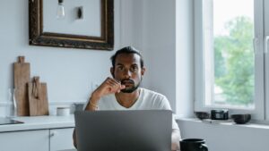 ノートパソコンの前で考え込む人のイメージ。カーリースの評判を検討する場面